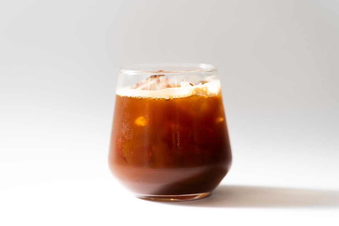 A refreshing iced Americano in a clear glass, showcasing rich coffee layers, contrasting with creamy milk-heavy coffee drinks.