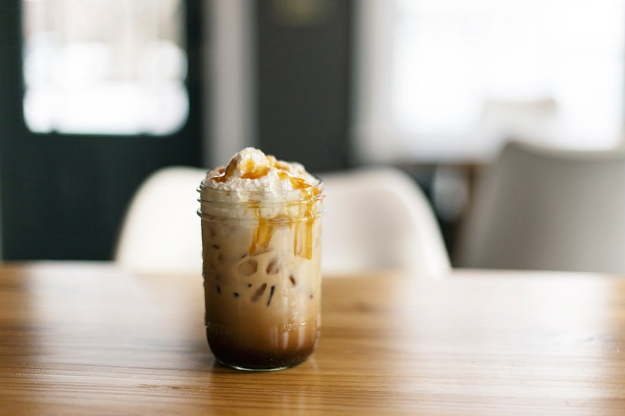 Two glasses side by side: one filled with creamy iced coffee and the other with a dark iced Americano, showcasing summer beverage options.