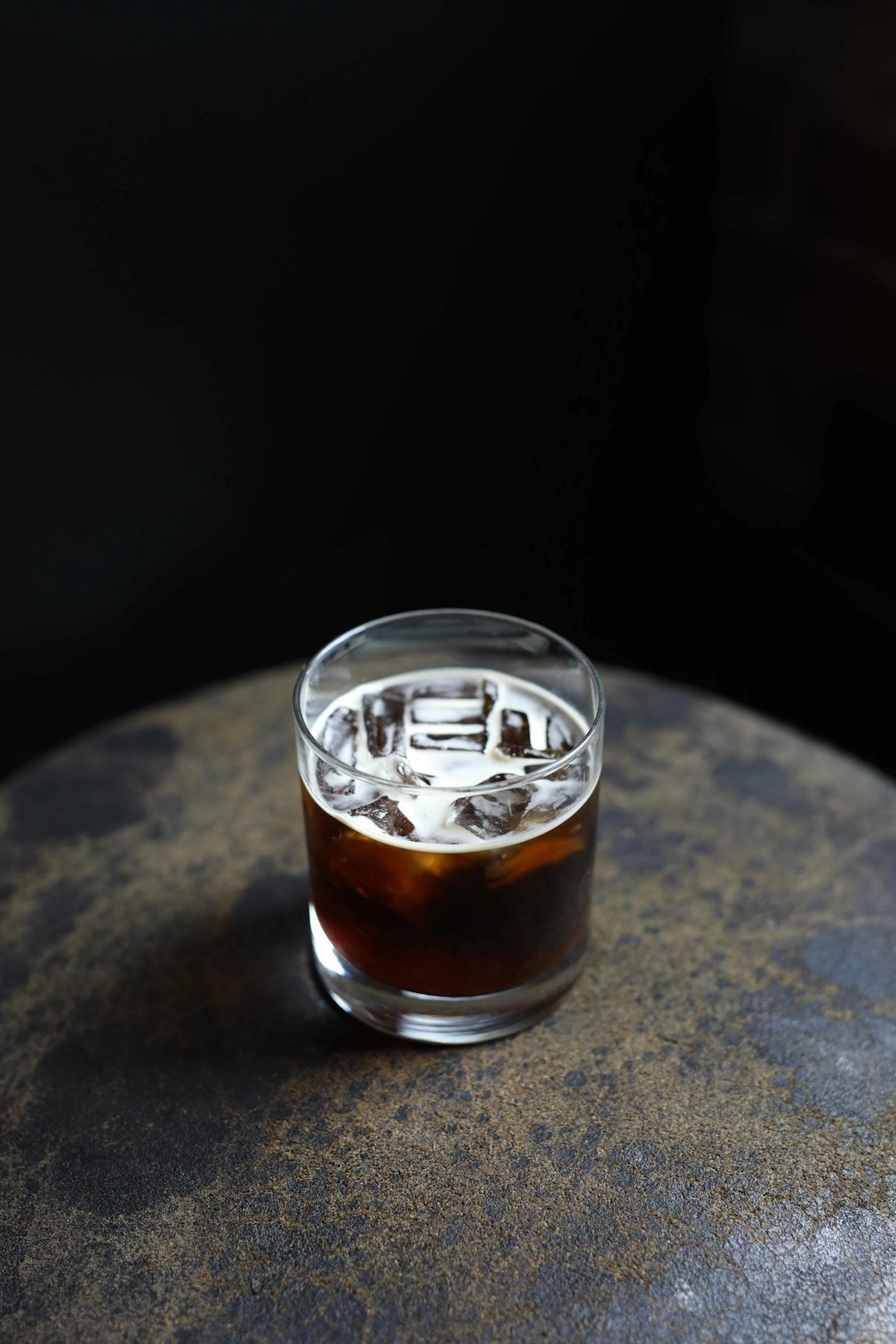 A refreshing iced Americano coffee in a clear glass, showcasing rich dark espresso and chilled water, perfect for hot days.