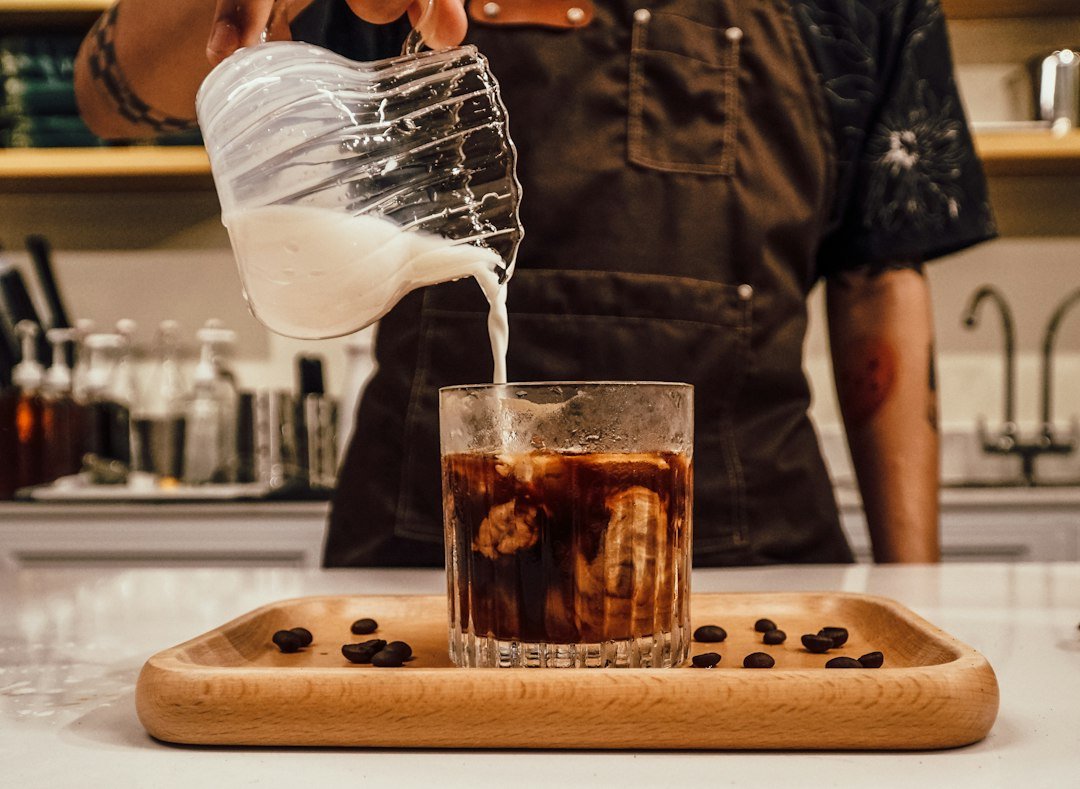 A refreshing glass of iced cold coffee with ice cubes, showcasing the rich, dark brew and frothy top.