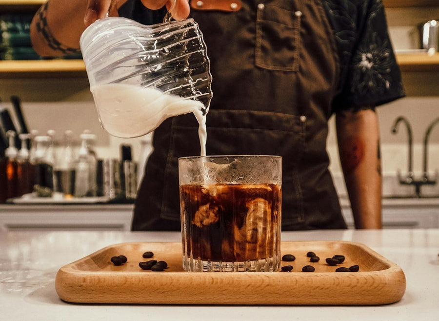 A refreshing glass of iced cold coffee with ice cubes, showcasing the rich, dark brew and frothy top.