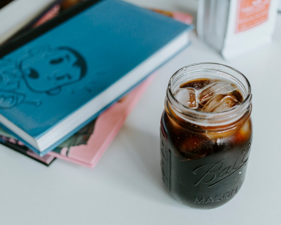A glass of cold French press coffee sits on a table, showcasing rich, dark brew with ice cubes, perfect for summer refreshment.