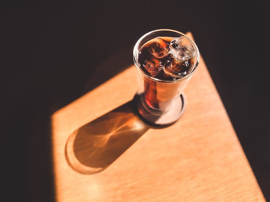 A refreshing Freddo Cappuccino sits on a wooden table, highlighting sustainability concerns in iced coffee consumption.